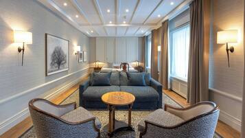 A hotel room with a blue sofa, two armchairs, a small round table, and wall-mounted lamps.