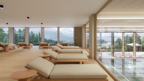 Ein Spa-Raum mit mehreren Liegen, einem Glaspool und Blick auf die Berge.
