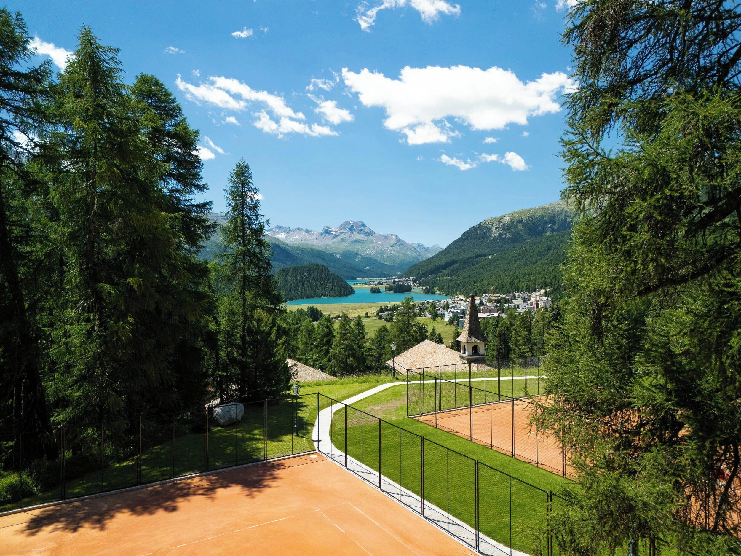 A scenic view of a mountainous landscape with a clear sky, a lake, and a town in the distance.