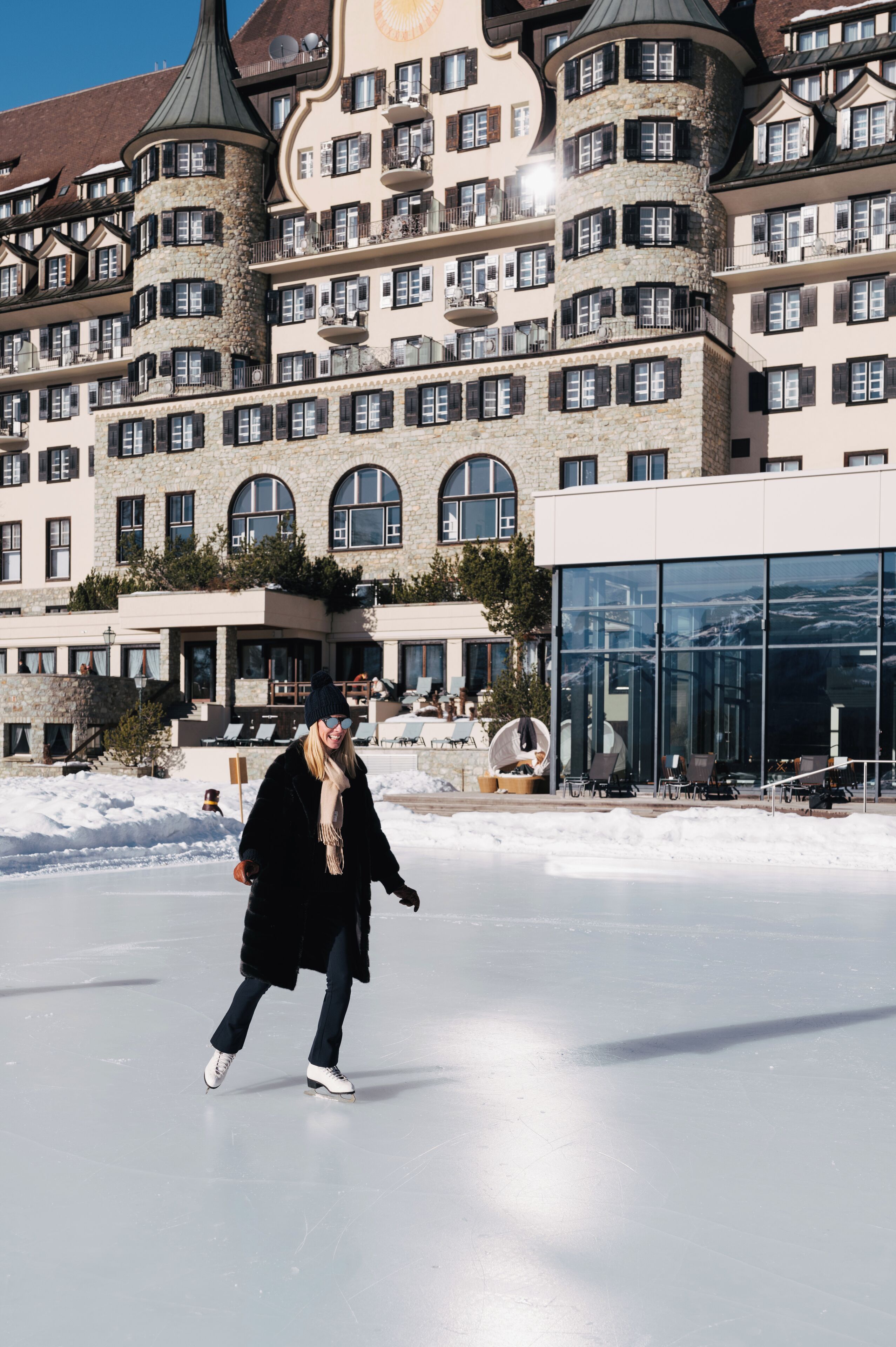 Een persoon schaatst voor een groot gebouw met meerdere balkons en een glazen gevel.
