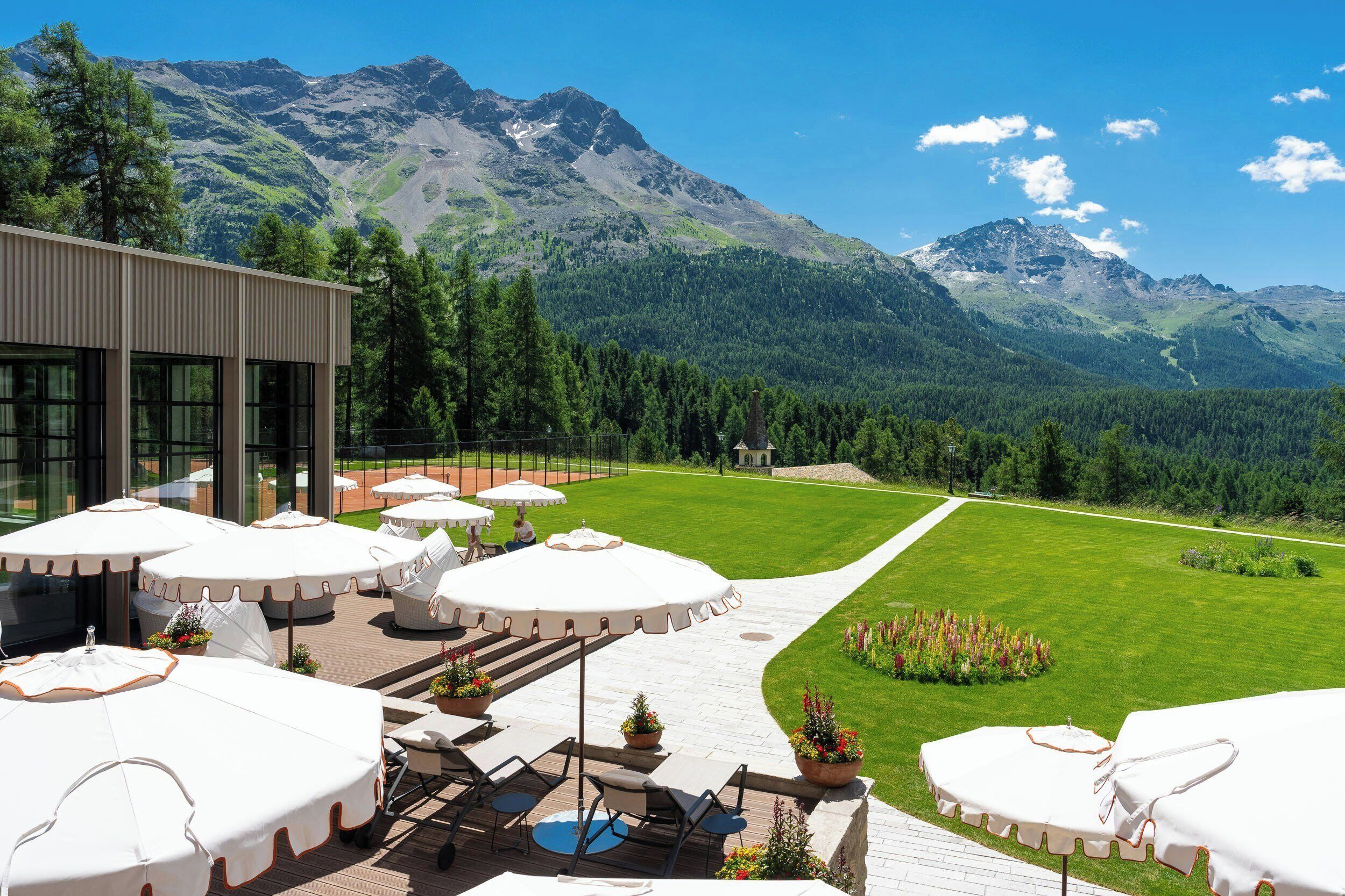 A terrace with outdoor seating and a view of a mountainous landscape.