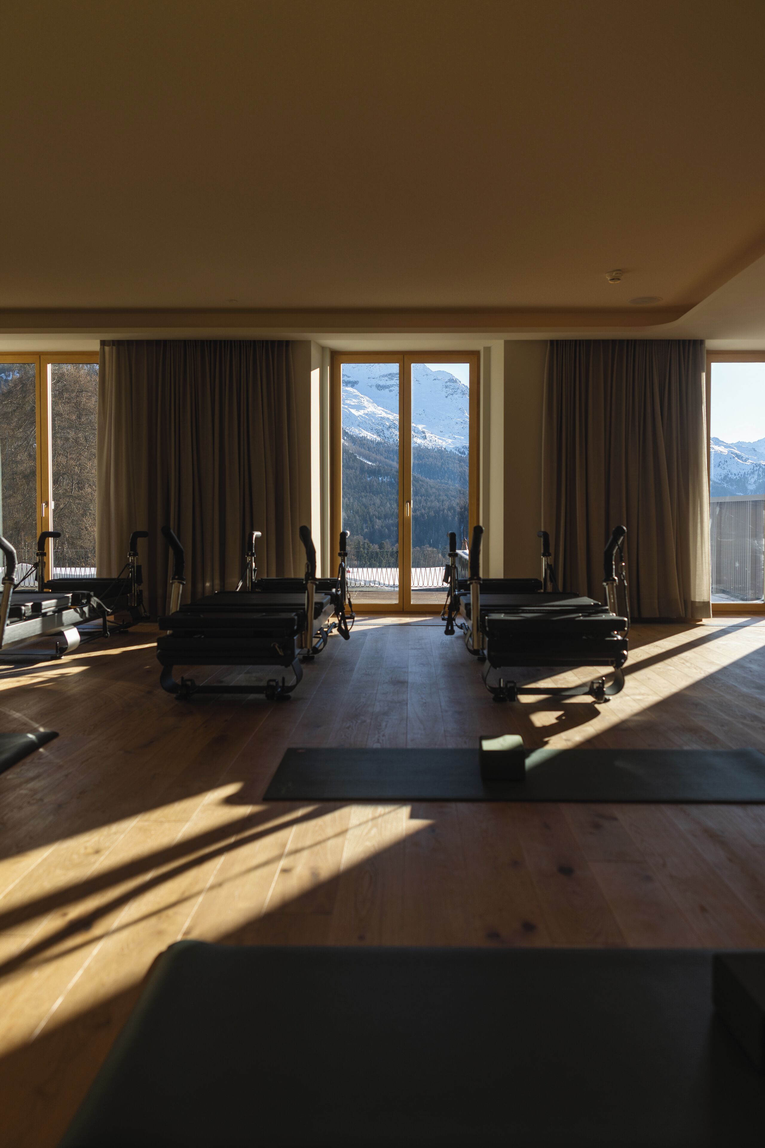 A spacious room with large windows, exercise equipment, and a view of mountains.