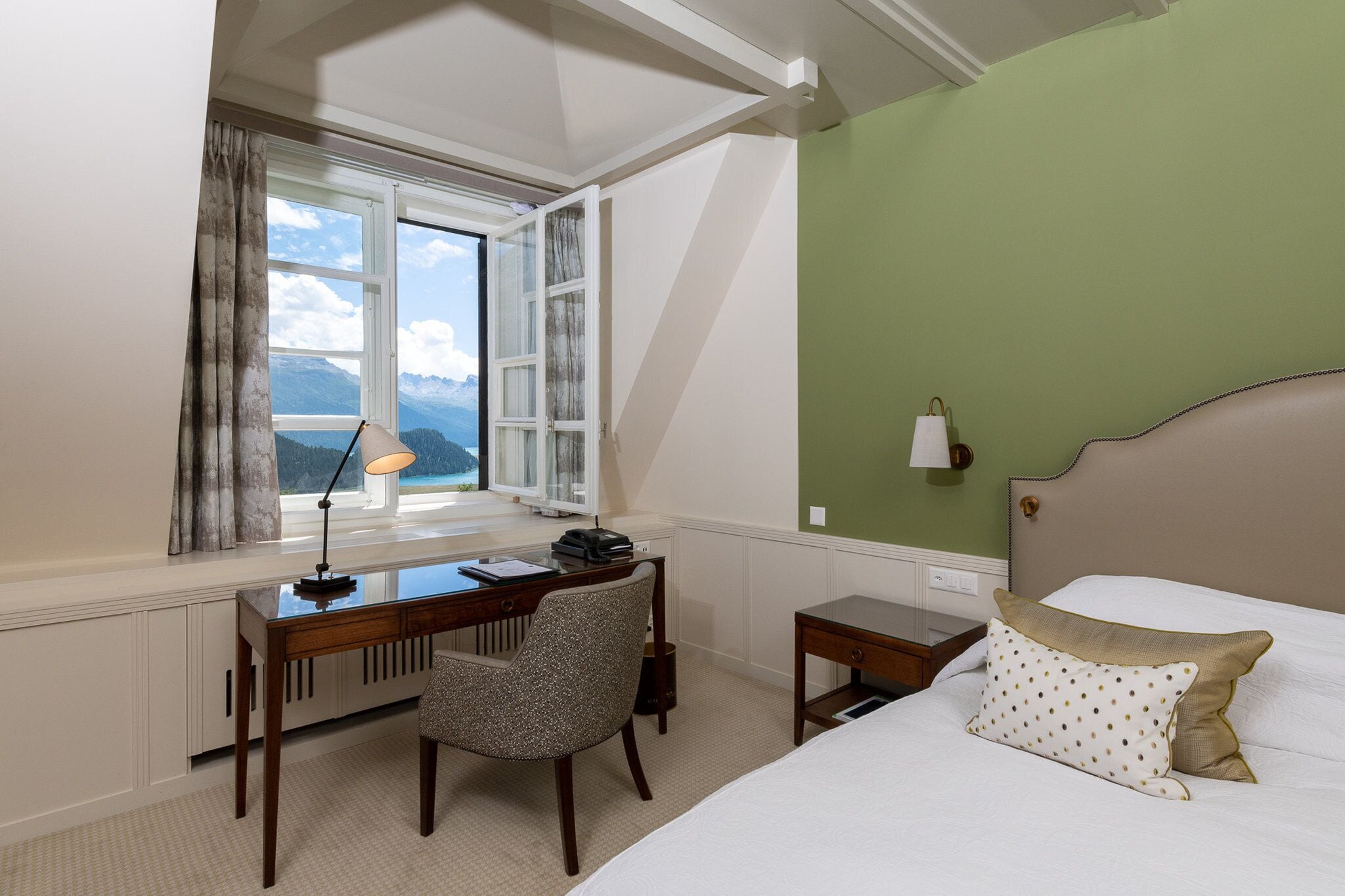 Una habitación de hotel con escritorio, silla y cama con almohadas.