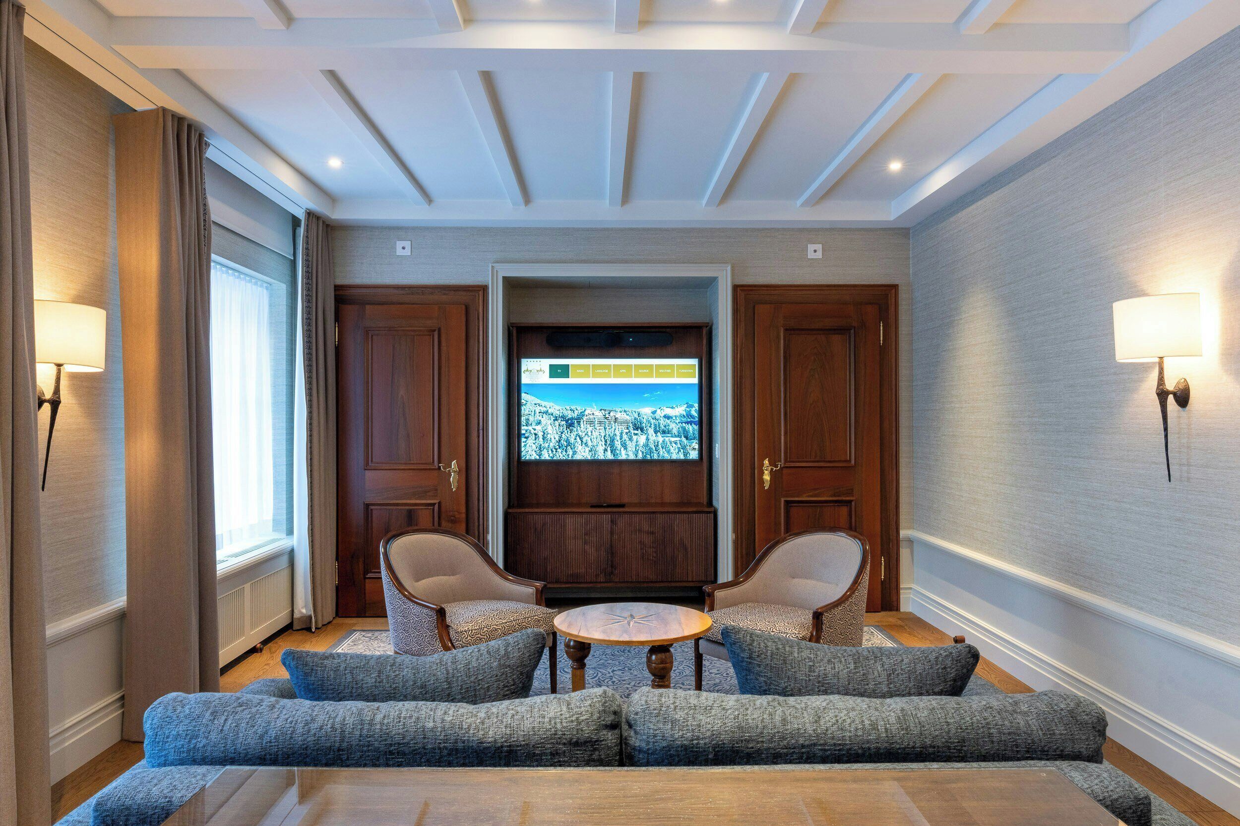 Un hall d’hôtel comprenant un espace salon, un écran de télévision et une porte en bois.