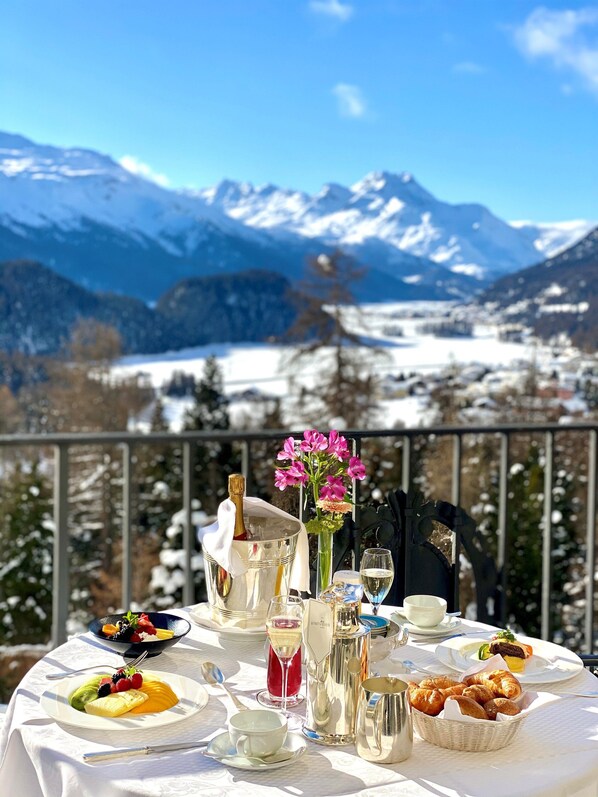 A table set for a meal with a mountain view in the background. - Suvretta House (St. Moritz)