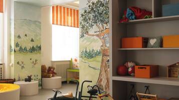 Un cuarto de juegos infantil con un mural grande, estantes con juguetes y un coche de juguete.
