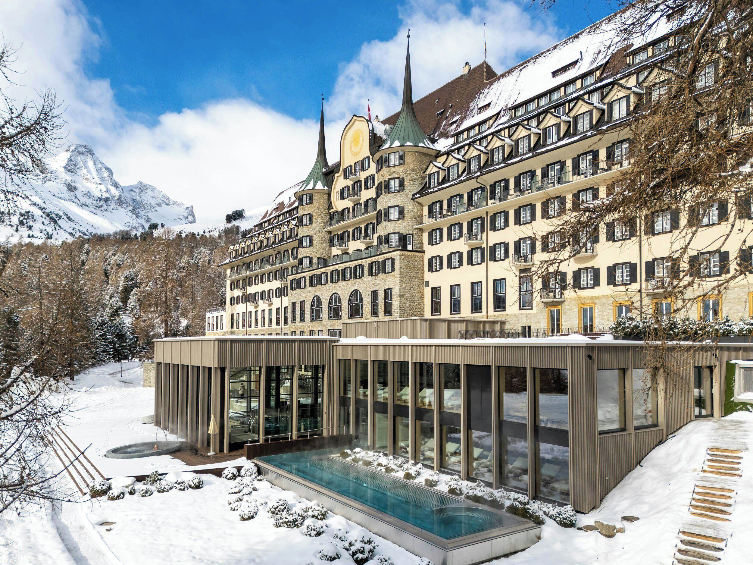 Un hôtel doté d’une piscine, entouré d’un paysage enneigé et avec des montagnes en toile de fond.