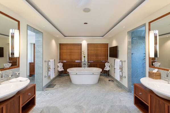 A modern bathroom with a freestanding bathtub, two sinks, and wooden paneling. - Suvretta House (St. Moritz)