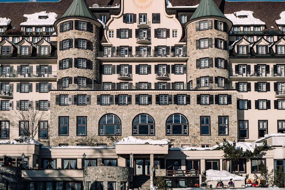 Un hotel histórico con varios pisos, una torre central y un techo cubierto de nieve.