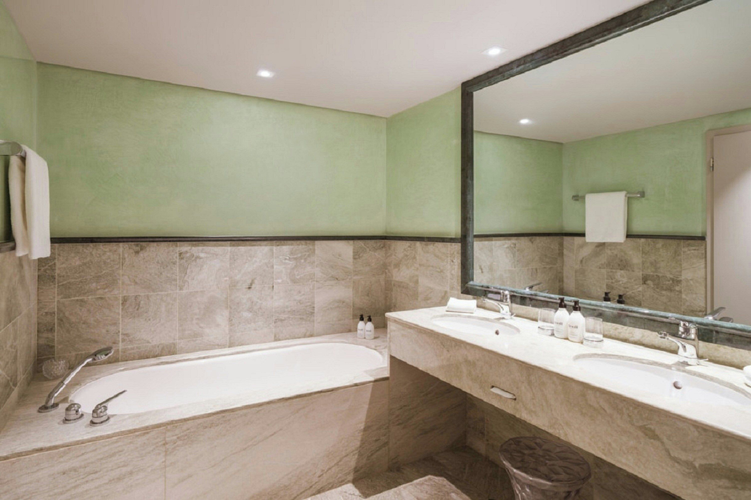 Une salle de bain avec une grande baignoire, deux lavabos et un miroir.