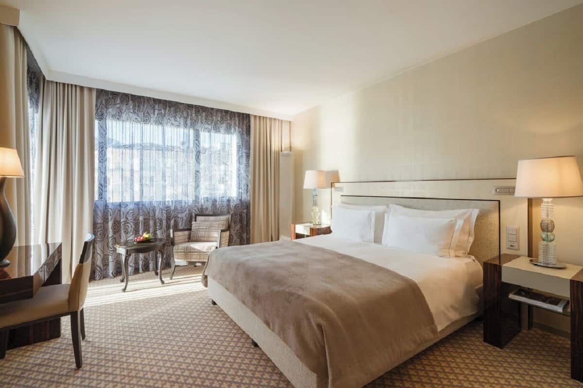 A hotel room with a large bed, two bedside tables, a desk, and a chair.