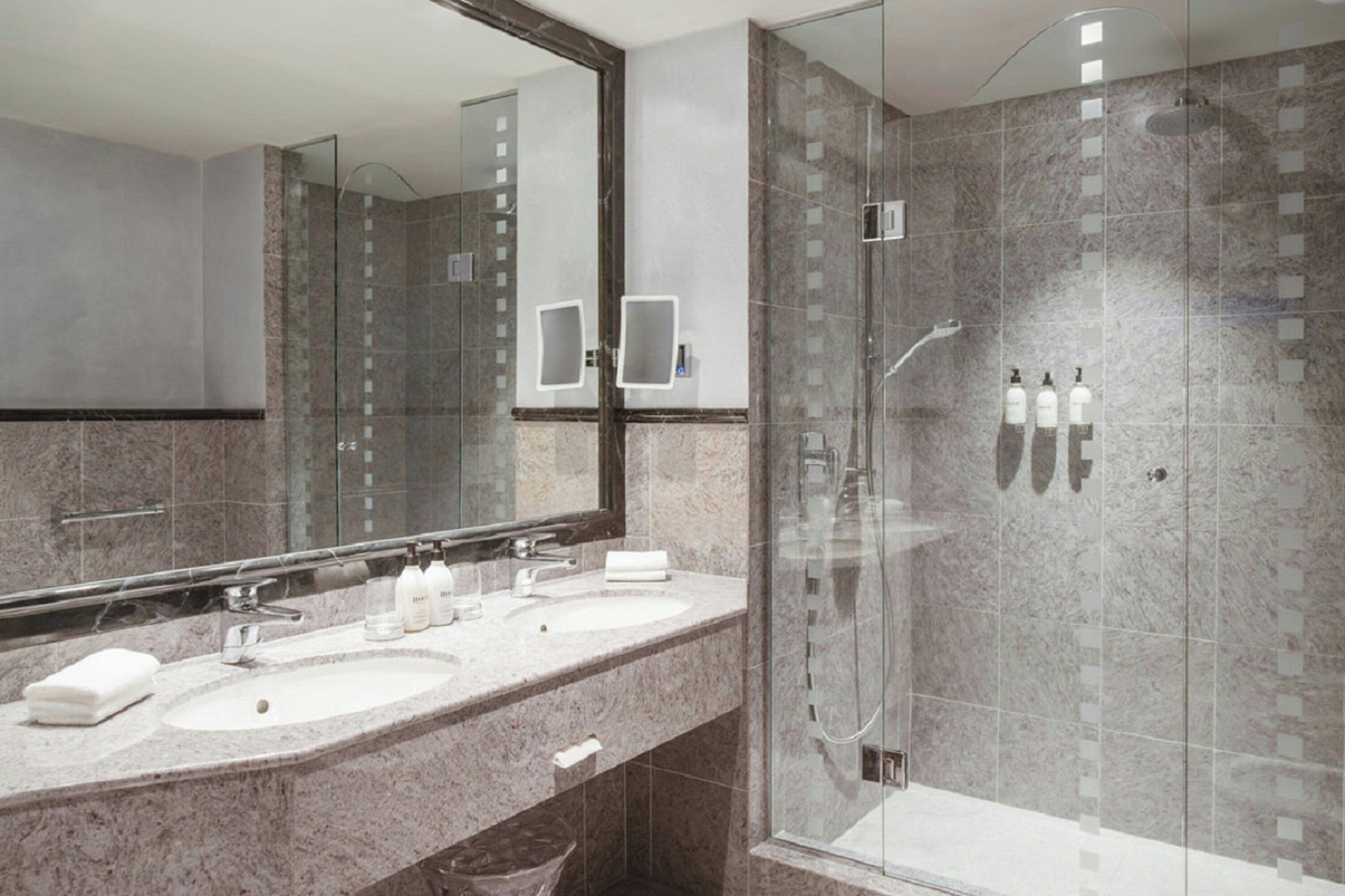 Ein modernes Badezimmer mit zwei Waschbecken, einem großen Spiegel und einer Duschkabine.