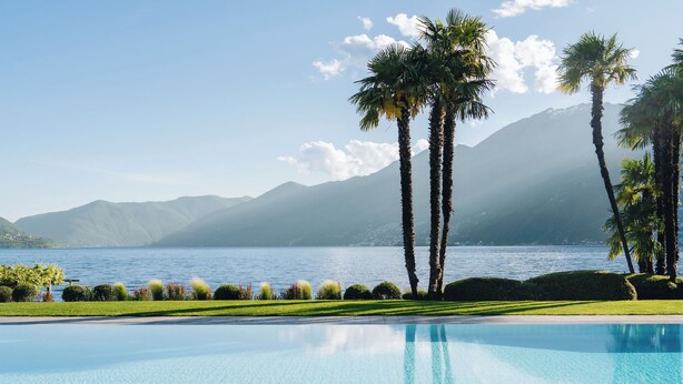 A swimming pool with a view of a lake and mountains. - Hotel Eden Roc (Ascona)