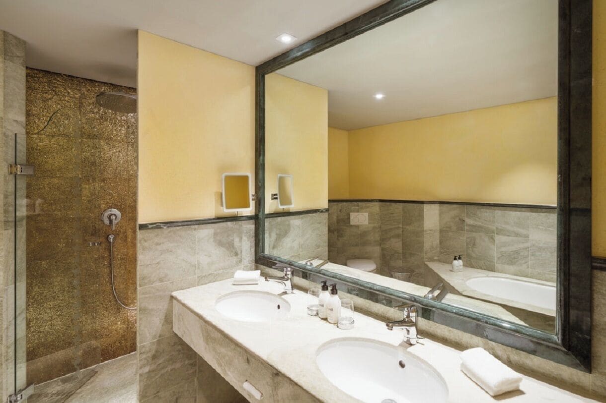 Un baño moderno con dos lavamanos, un espejo grande y zona de ducha.