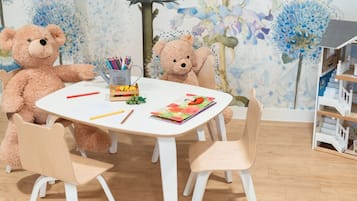 Children can play and create at this vibrant playroom with a table, chairs, and art supplies.