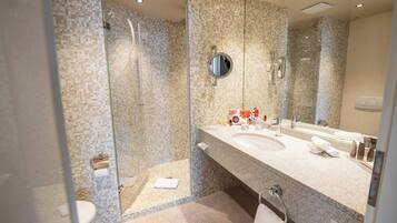 Un baño moderno con ducha acristalada, un espejo grande y encimera de granito.