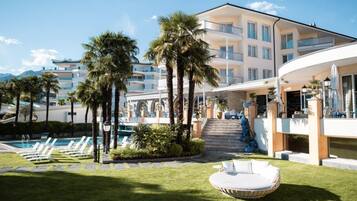 Relax by the pool with a view of the lush lawn and palm trees from the hotel's curved balcony.