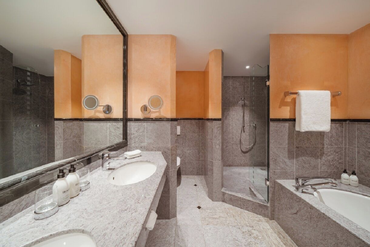 A modern bathroom with two sinks, a bathtub, and a shower.