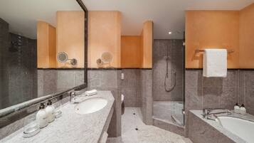 A modern bathroom with two sinks, a bathtub, and a shower.