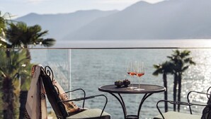 A balcony with a table, two chairs, and a pair of shoes. - Hotel Eden Roc (Ascona)