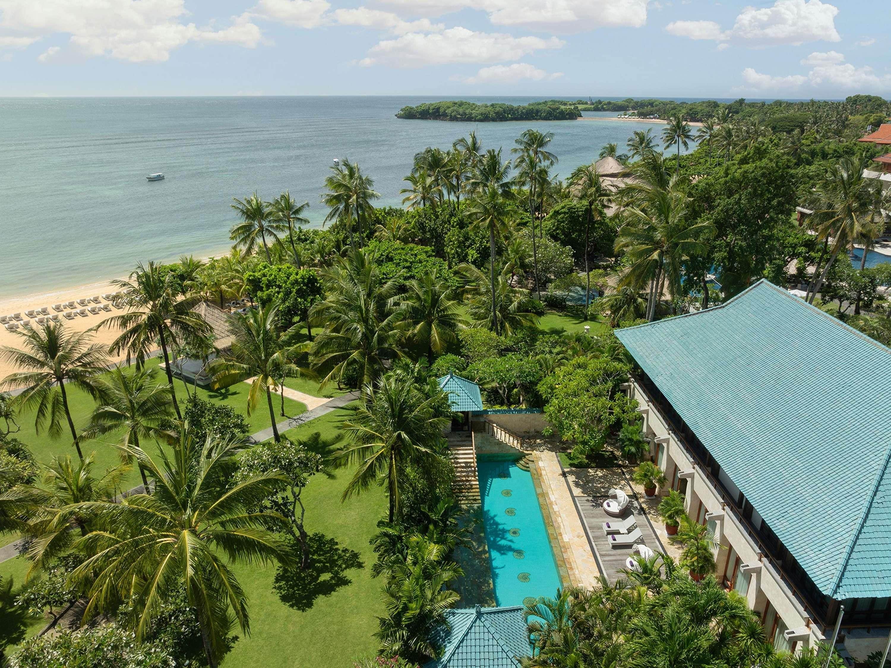 A resort with a pool, beach, and tropical vegetation.