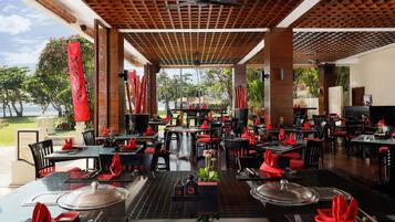 A restaurant with outdoor seating, red napkins, and a view of the ocean.