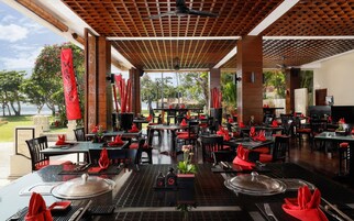A restaurant with outdoor seating, red napkins, and a view of the ocean.