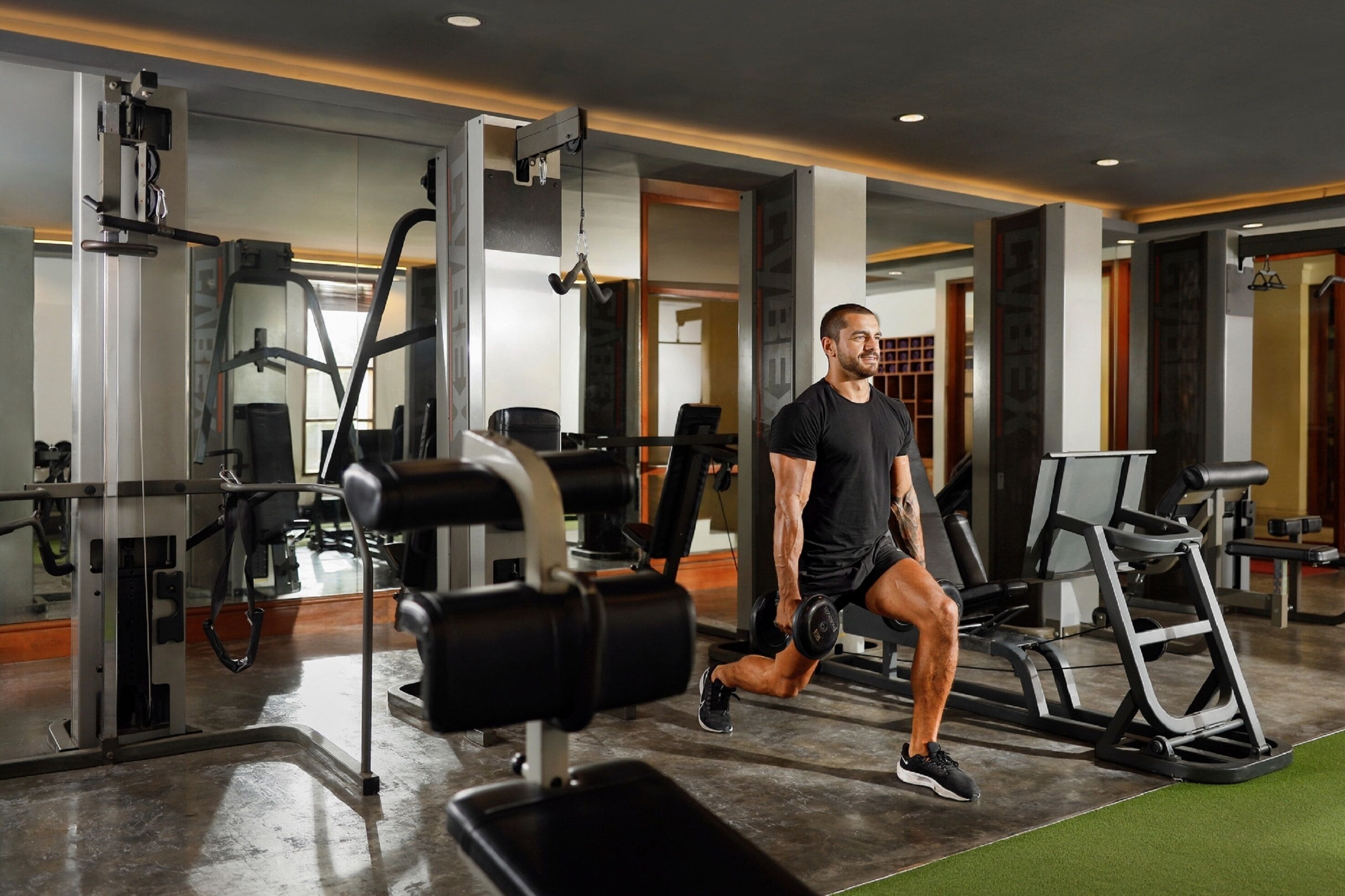 Un gimnasio con diversos equipos de ejercicio, incluyendo cintas de correr y máquinas de pesas.
