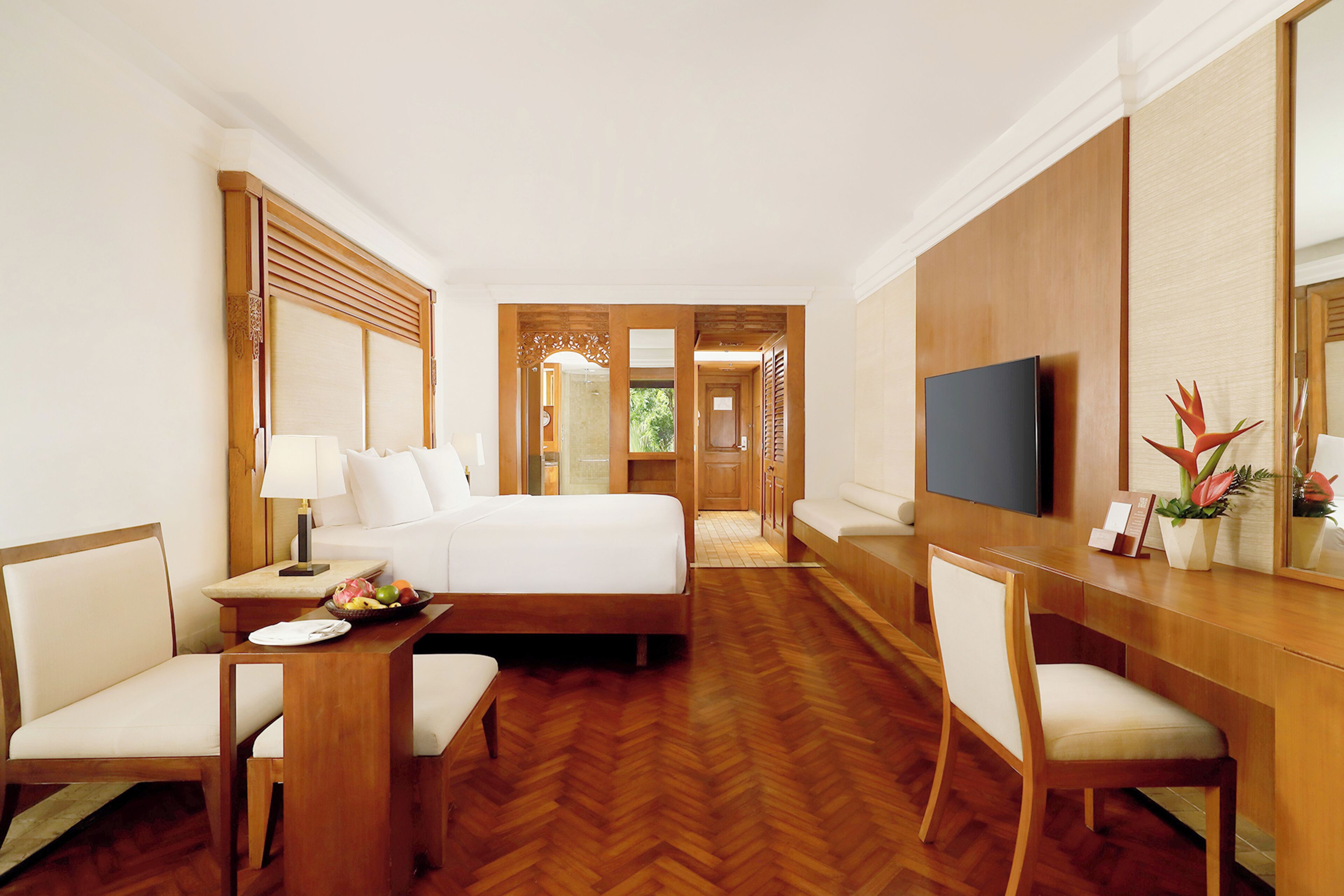 A hotel room with a bed, a desk, a chair, a television, and a mirror.