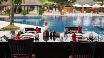 Mesa de comedor para dos con vista a una piscina y zona de estar.