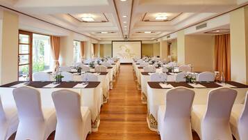 A conference room with rows of tables and chairs, equipped with water bottles and glassware.