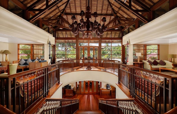 A grand lobby with a wooden staircase, large windows, and a chandelier. - Nusa Dua Beach Hotel and Spa - Handwritten Collection (Nusa Dua)