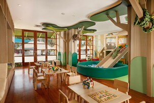 A children's play area with a slide, seating, and tables.