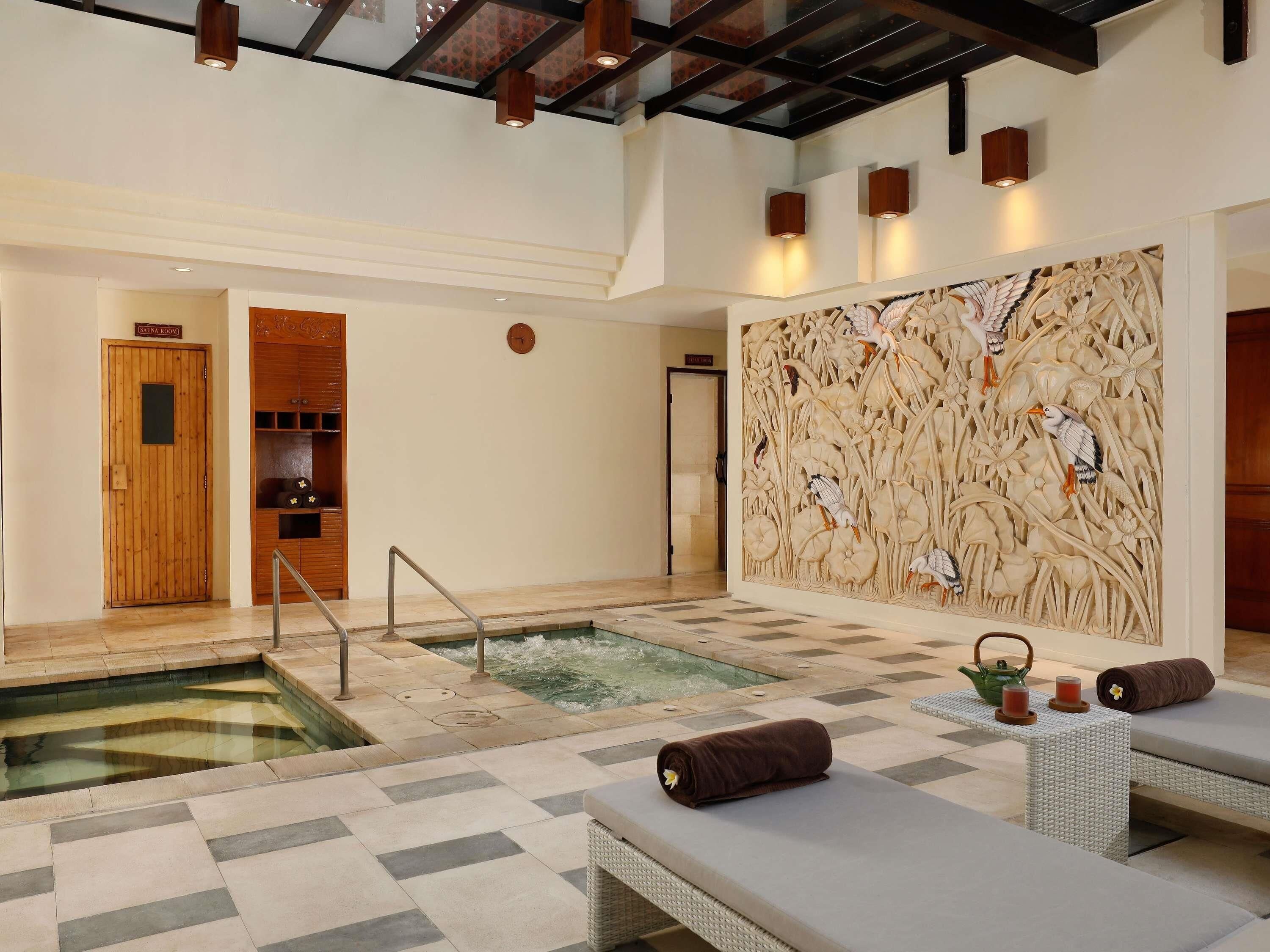 Un espacio de spa con jacuzzi, sillones reclinables y una pared decorativa.