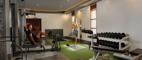 A gym with exercise equipment, a weight bench, and a rack of dumbbells.