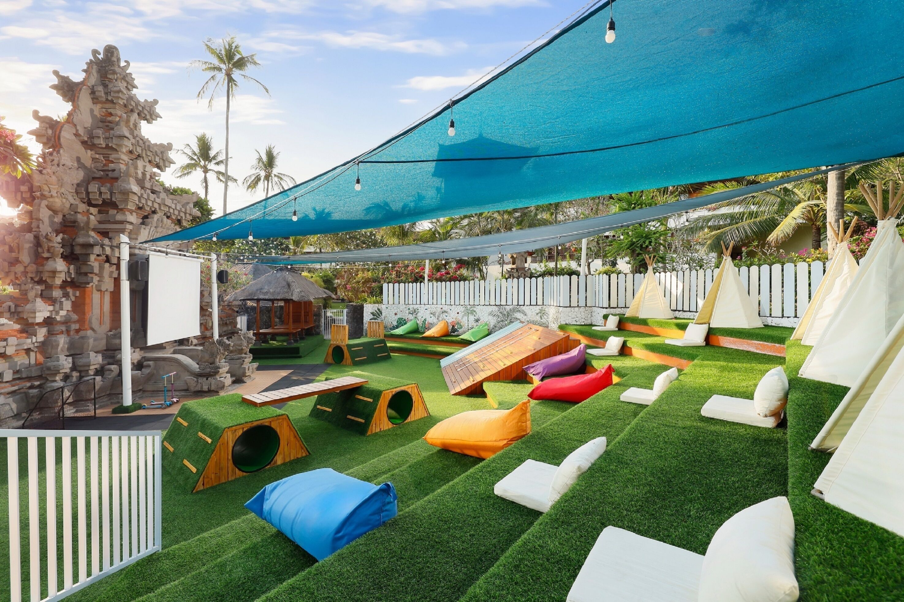 A children's play area with artificial grass, play structures, and seating areas.