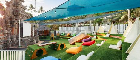 A children's play area with artificial grass, play structures, and seating areas.