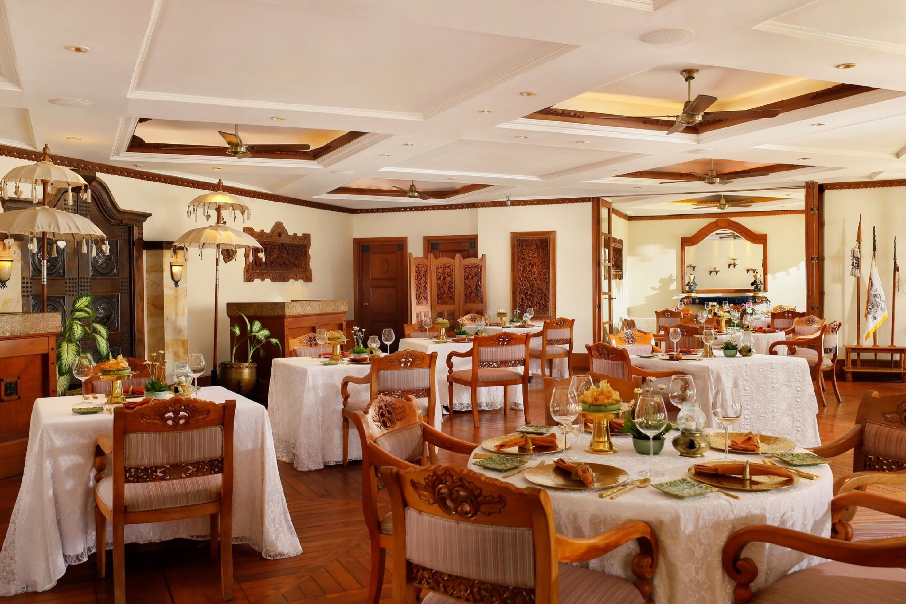 A dining area with round tables, wooden chairs, and chandeliers.