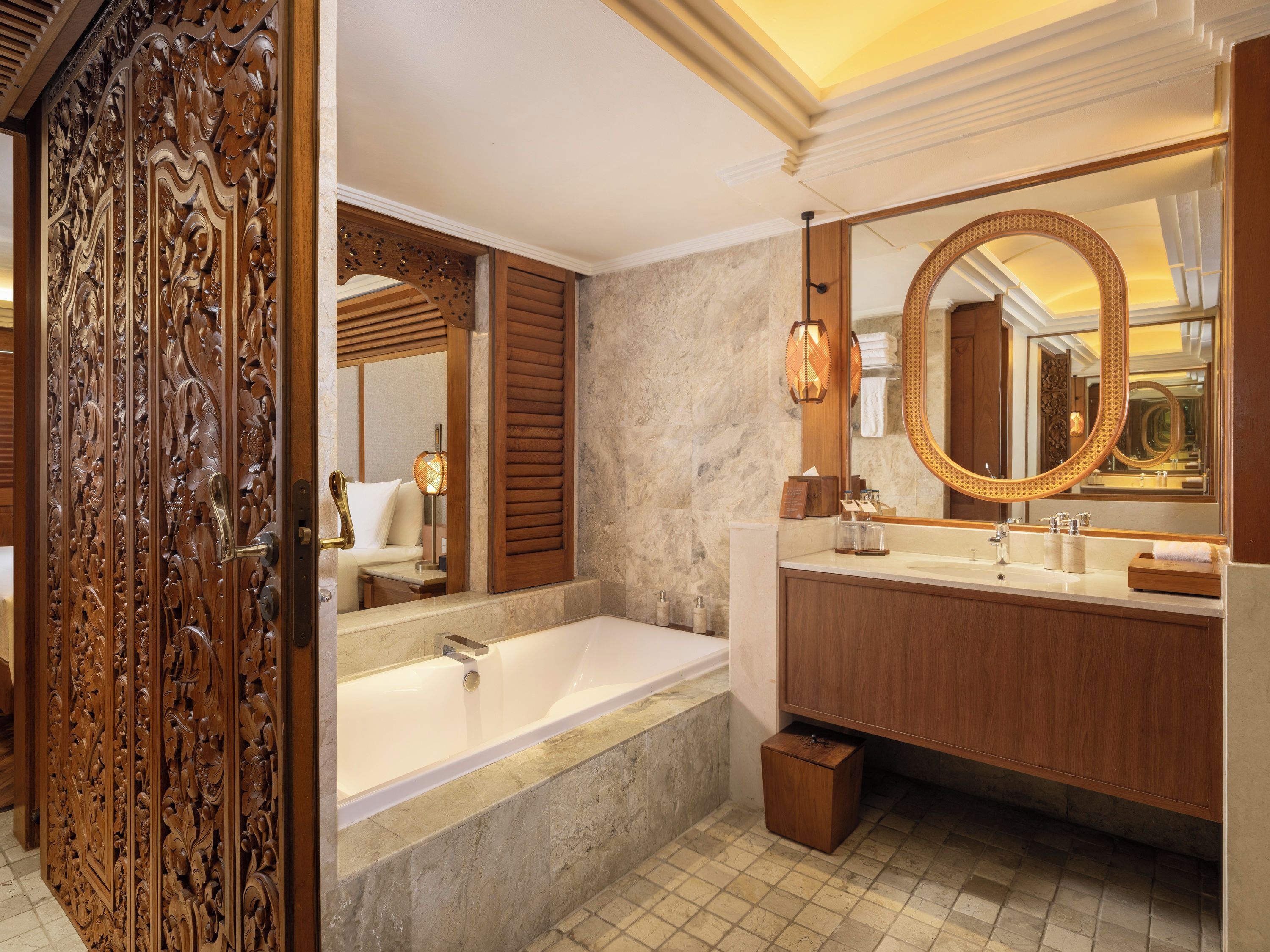A luxurious bathroom with a marble floor, a freestanding bathtub, a wooden vanity with a large mirror, and a decorative wooden panel.