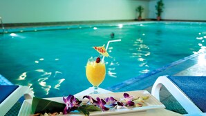 Un cadre agréable au bord de la piscine, avec une boisson, des fleurs et un fauteuil de relaxation.