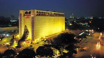 A large hotel with a prominent arched entrance and a well-lit facade at night.