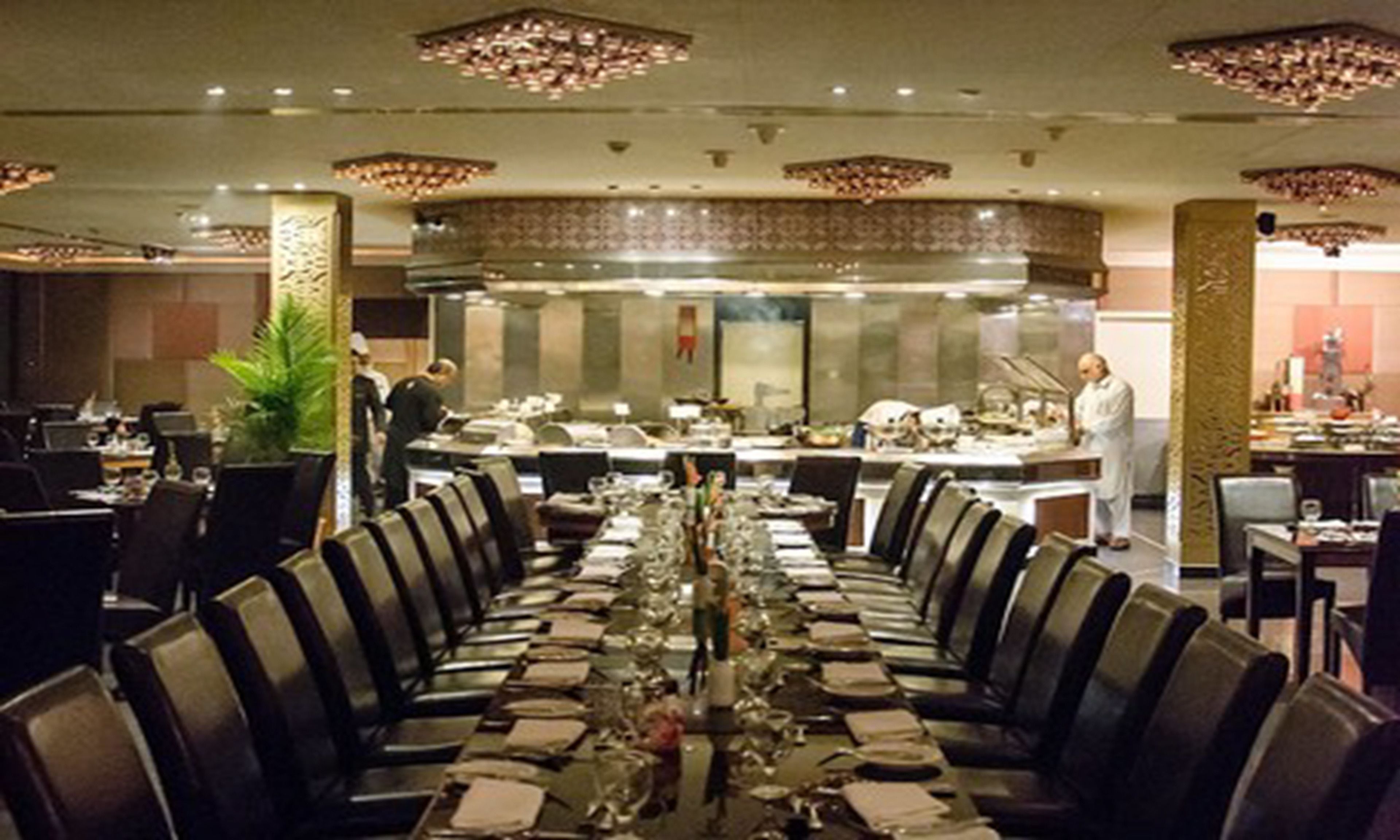 A formal dining room with a long table set for a meal, surrounded by chairs.
