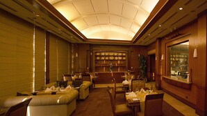 Un hall d’hôtel doté d’un plafond incurvé, de coins salon, d’un bar et d’une exposition d’assiettes.