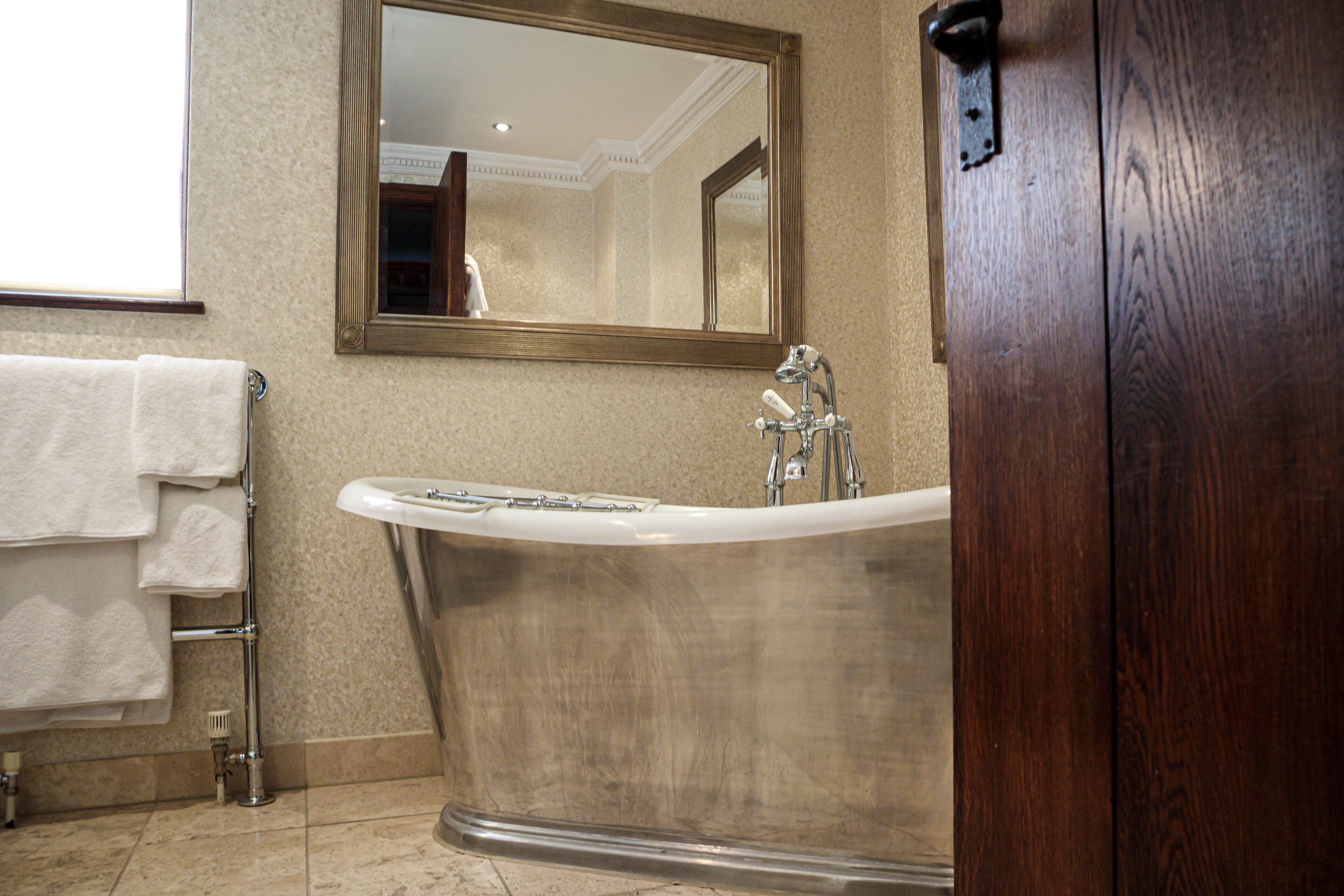 A bathroom with a freestanding bathtub, a sink, and a mirror.