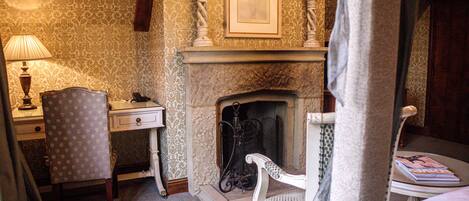 Una habitación con chimenea, un escritorio con lámpara y dos sillas.