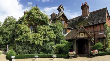 A traditional Tudor-style building with a steeply pitched roof, timber framing, and a prominent chimney.