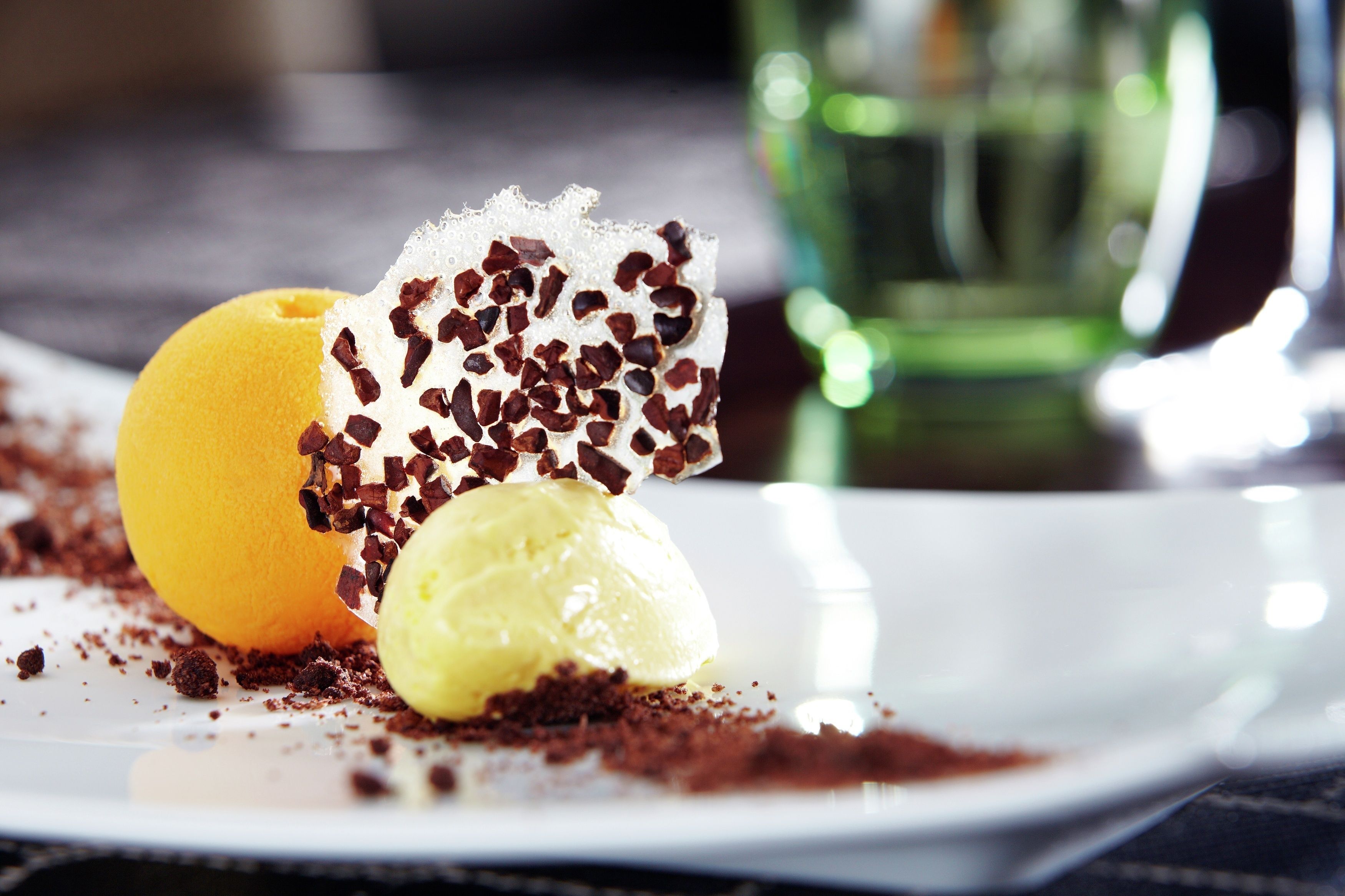 Une assiette à dessert avec une boule de glace, une part de gâteau et des copeaux de chocolat.