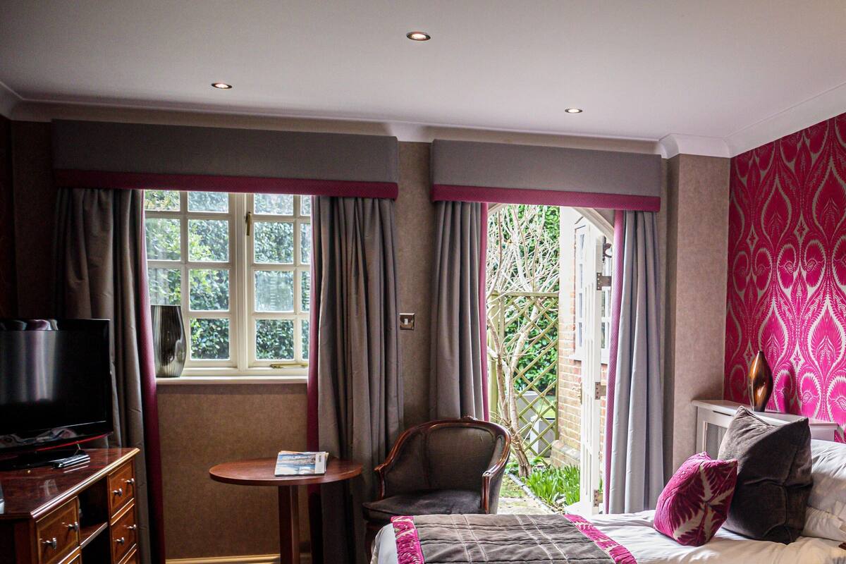 A hotel room with a bed, a television, a small table, and a chair.