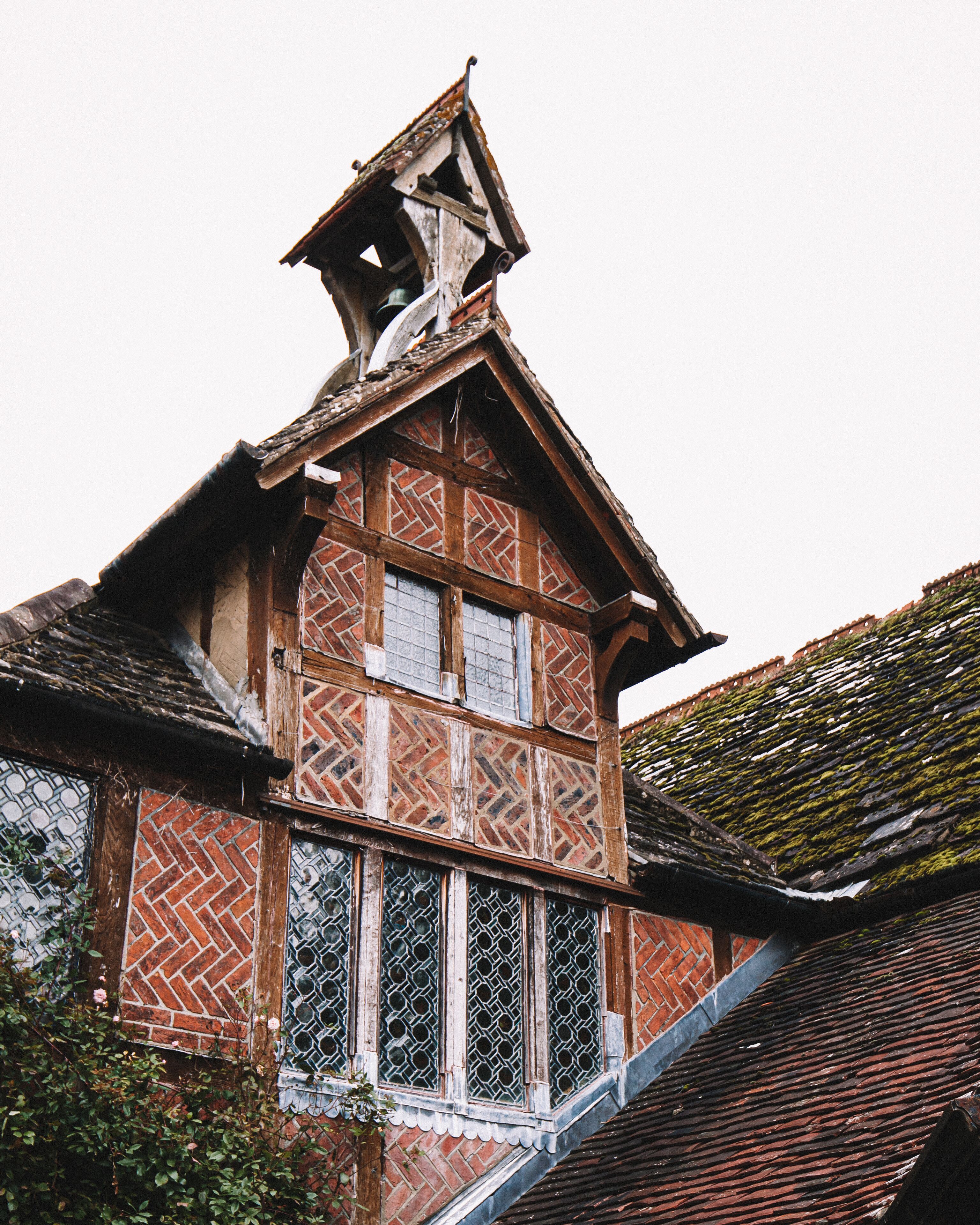 A traditional half-timbered house with a steeply pitched roof, a bell tower, and a small balcony.