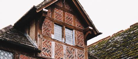 A traditional half-timbered house with a steeply pitched roof, a bell tower, and a small balcony.